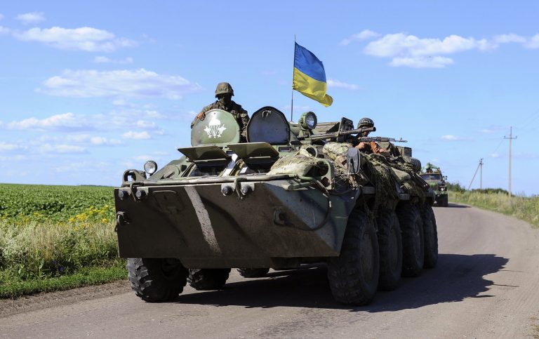 Ukrainian soldiers drive a military vehicle with a Ukrainian flag at a checkpoint near Slaviansk in eastern Ukraine July 3, 2014. About half the 130,000 residents of Slaviansk are thought to have fled since fighters who want eastern Ukraine incorporated into Russia took control of the city in April, a month after Moscow annexed the Black Sea peninsula of Crimea. Since then, government forces trying to end the rebellion in towns and cities across the Russian-speaking region have pounded separatist positions in and around Slaviansk. Picture taken July 3, 2014. REUTERS/Andrew Kravchenko/Pool (UKRAINE - Tags: POLITICS CIVIL UNREST MILITARY)